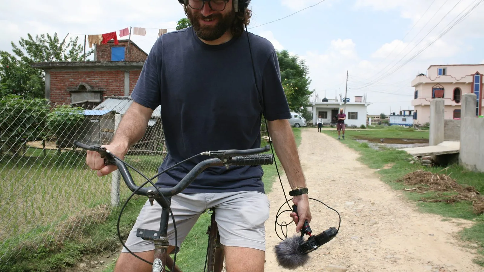 Gimbal operator riding a bicycle down a dirt road in Nepal