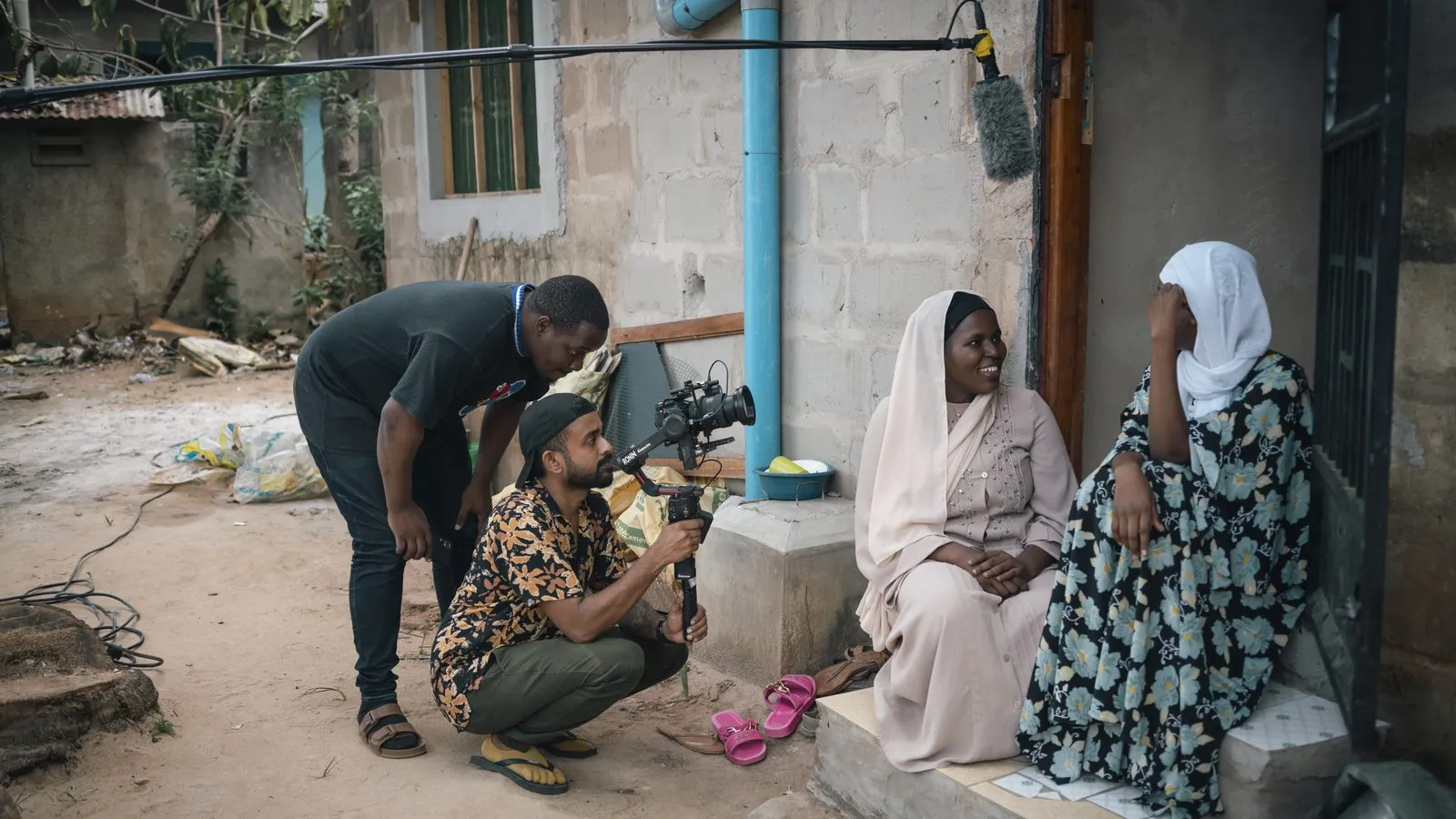 Crew crouched at eye level filming two seated women in Tanzania