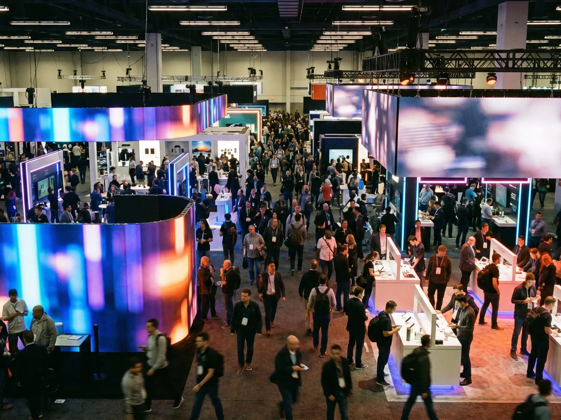 Consumer electronics show floor with curved LED walls and crowds