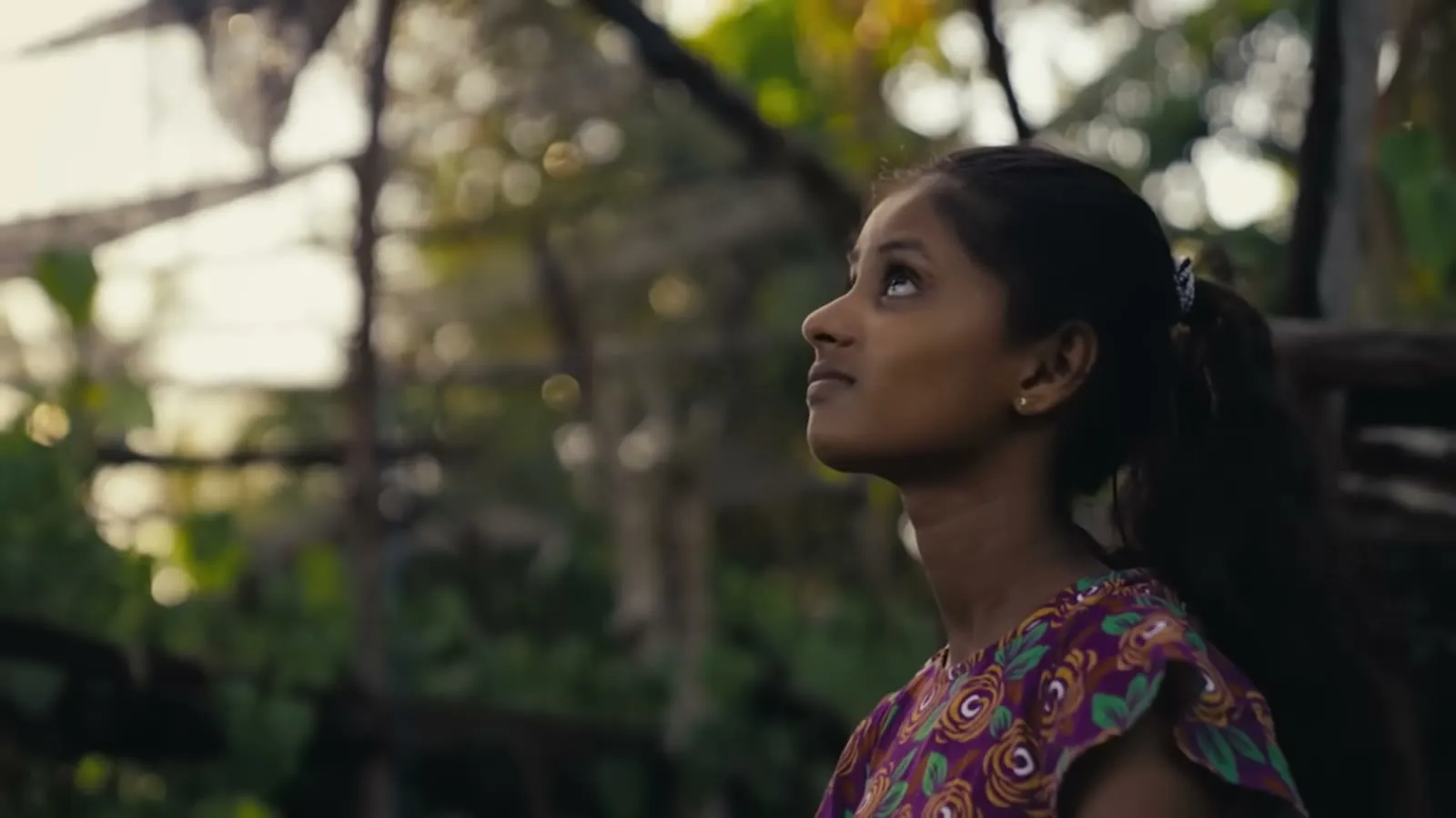 A girl looks up in natural light in a still from the She Creates Change documentary trailer