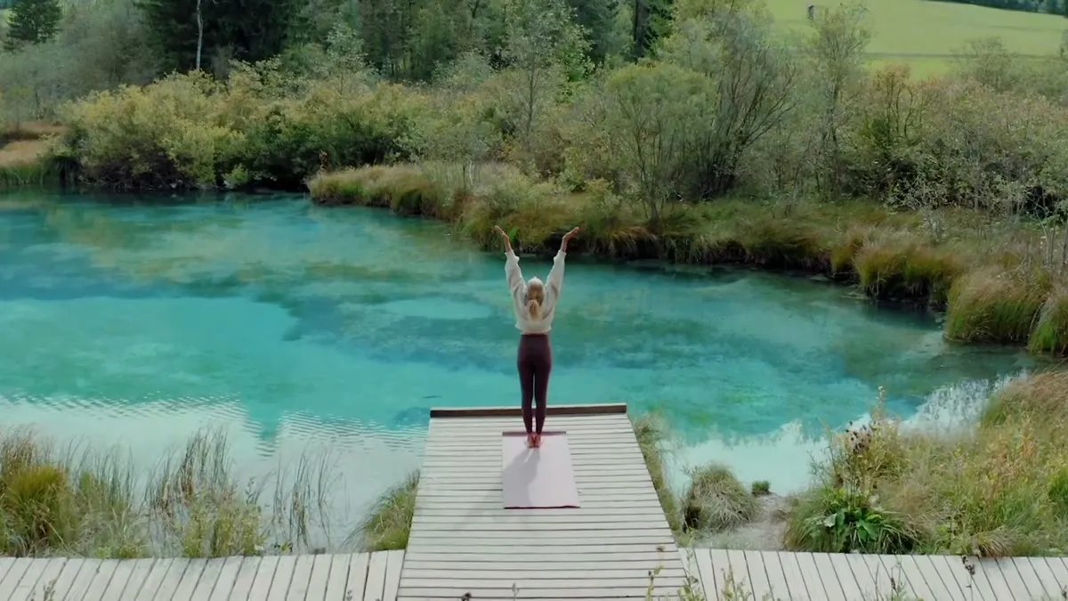 A woman on a wooden dock with arms raised facing a turquoise spring, from the Securonix brand film