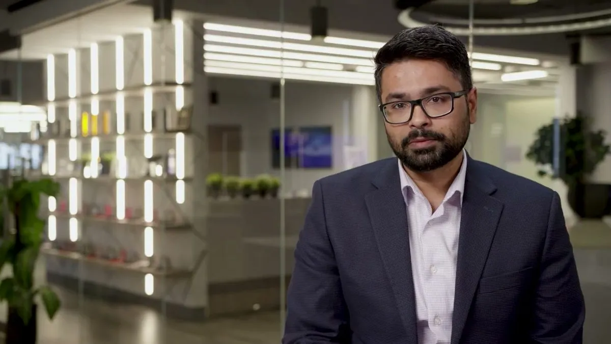Aditya Sundararam of Securonix in a suit, interviewed in a glass-walled office, from the Threat Labs customer story